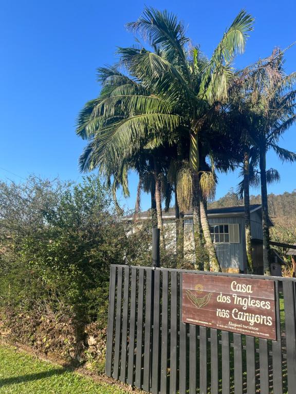 un panneau devant une maison plantée de palmiers dans l'établissement Casa dos Ingleses nos Canyons, à Praia Grande