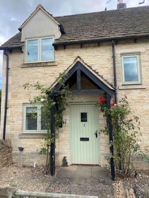 a brick house with a white door and flowers at Cotswold Cottage in Cheltenham