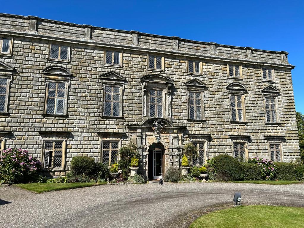 a large stone building with a driveway in front of it at Moresby Hall Country House Hotel in Whitehaven