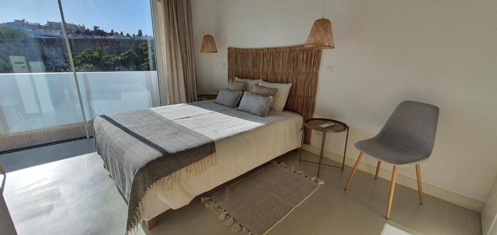 um quarto com uma cama, uma cadeira e uma janela em Lemon Villa em Lagos