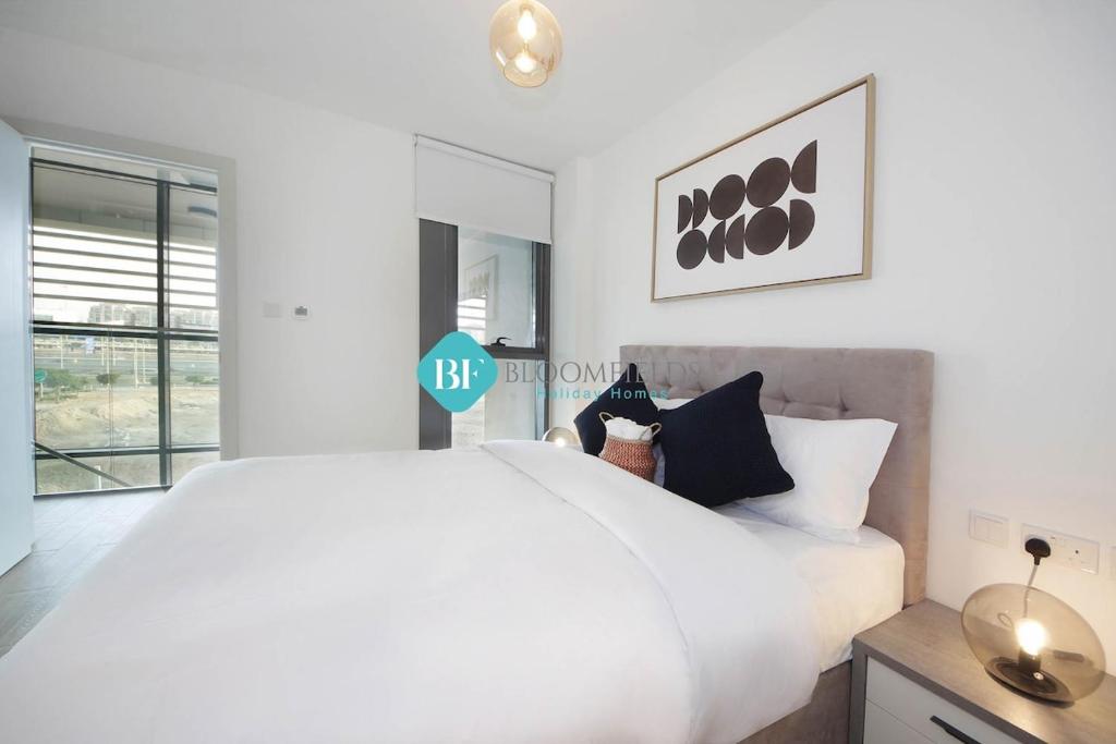 a white bedroom with a large bed and a window at Luxury Duplex In Raha Lofts in Abu Dhabi