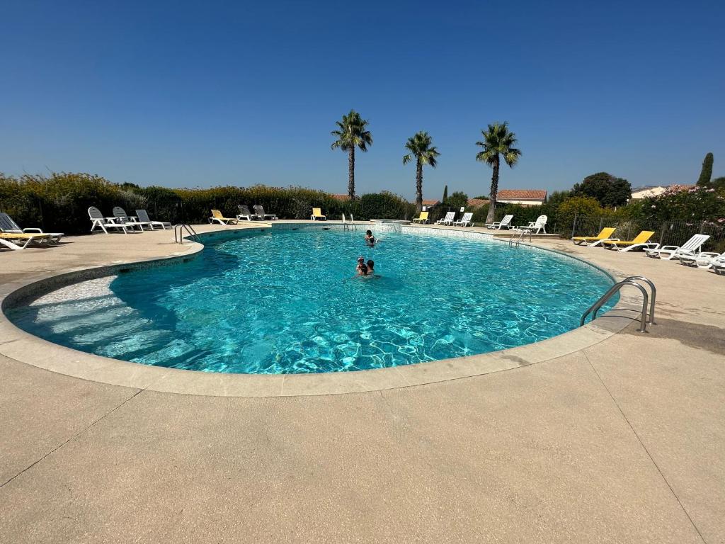 - une piscine avec des chaises et des palmiers dans l'établissement Villa 5 min circuit Paul-Ricard et 20 mn de la Mer, à Signes