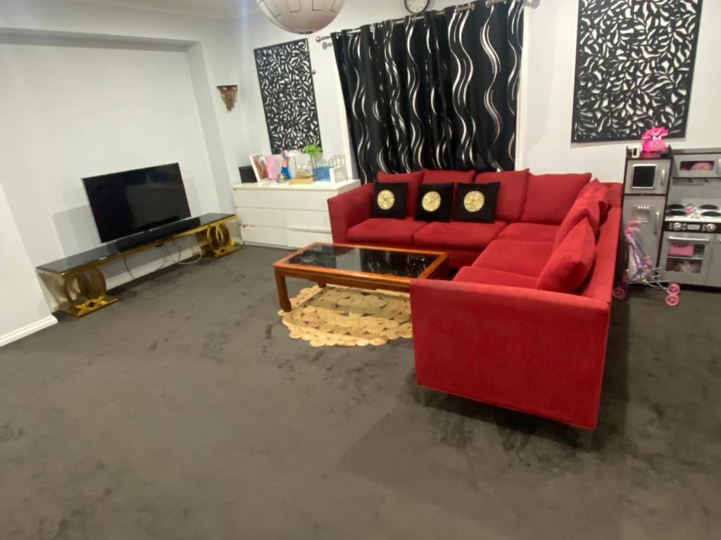 een woonkamer met een rode bank en een tv bij Private room in shared house in Wollert