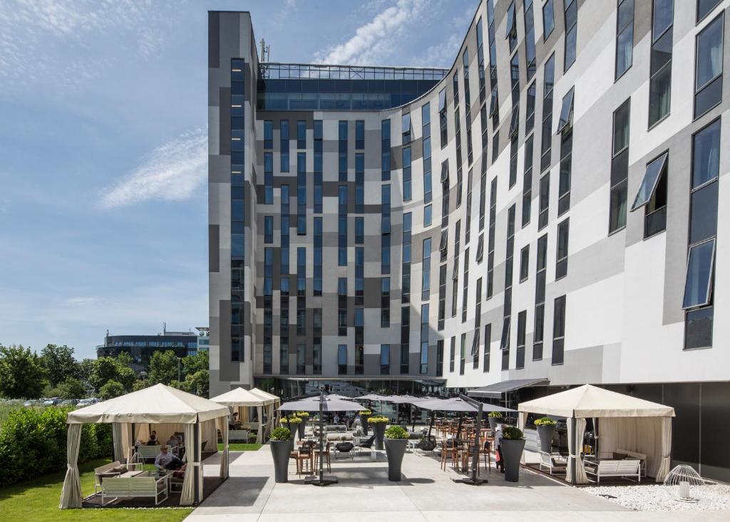 un edificio con mesas y sombrillas delante en Falkensteiner Hotel Belgrade, en Belgrado