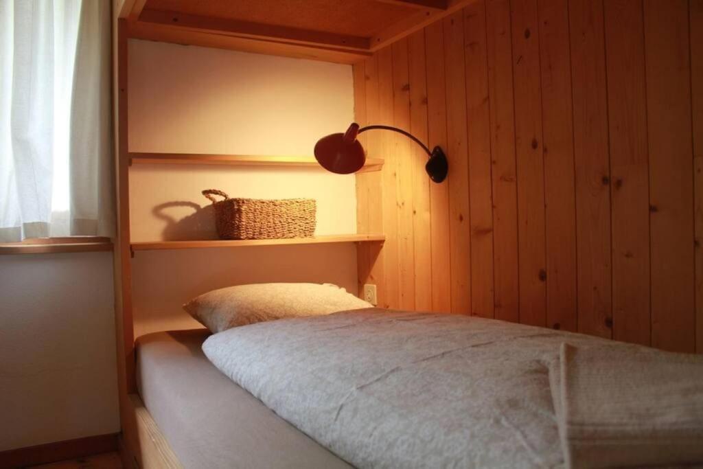 a bedroom with a bed and a lamp on a shelf at NEB-THUN Seehaus Einigen in Einigen