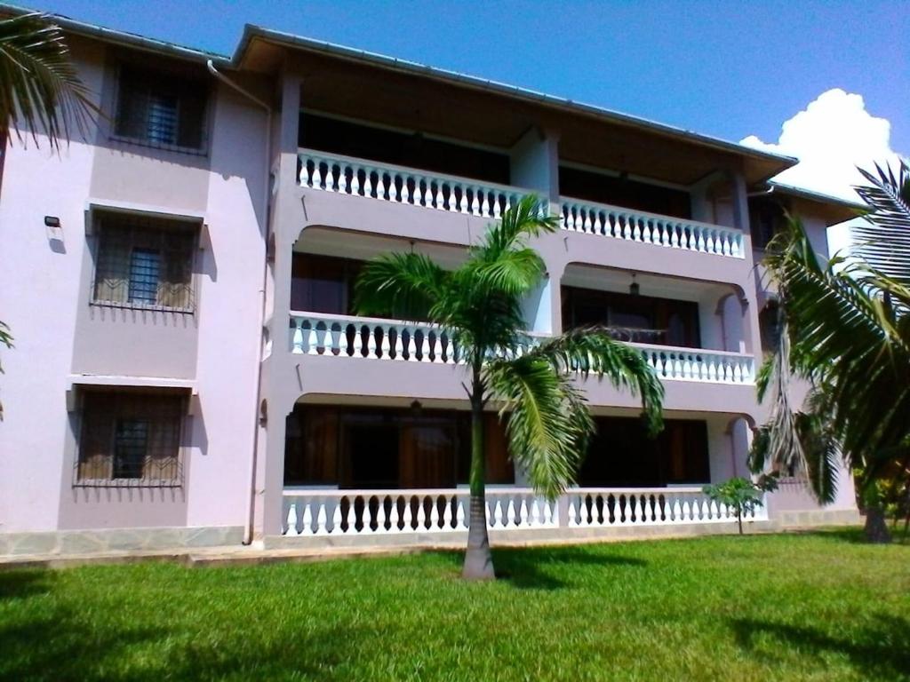 un edificio con una palmera delante de él en Galu Gardens Diani Beach ,Coastal Apartments by Nest & Nomad en Kwale