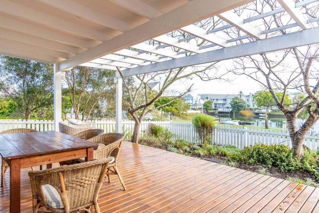 a wooden deck with a wooden table and chairs at Peaceful Parkland Home on Thesen Islands in Knysna