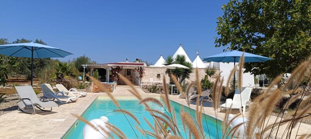 a swimming pool with chairs and umbrellas at Il Trullo di Heidi in Ostuni