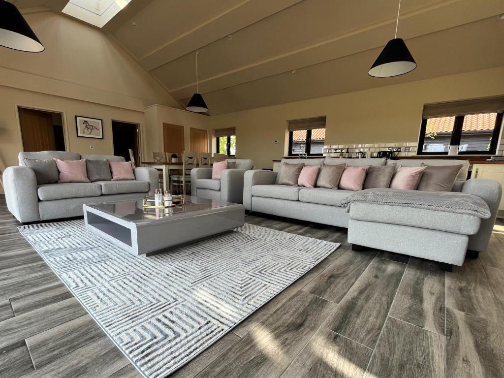 a large living room with couches and a table at White House Lodges in Heveningham