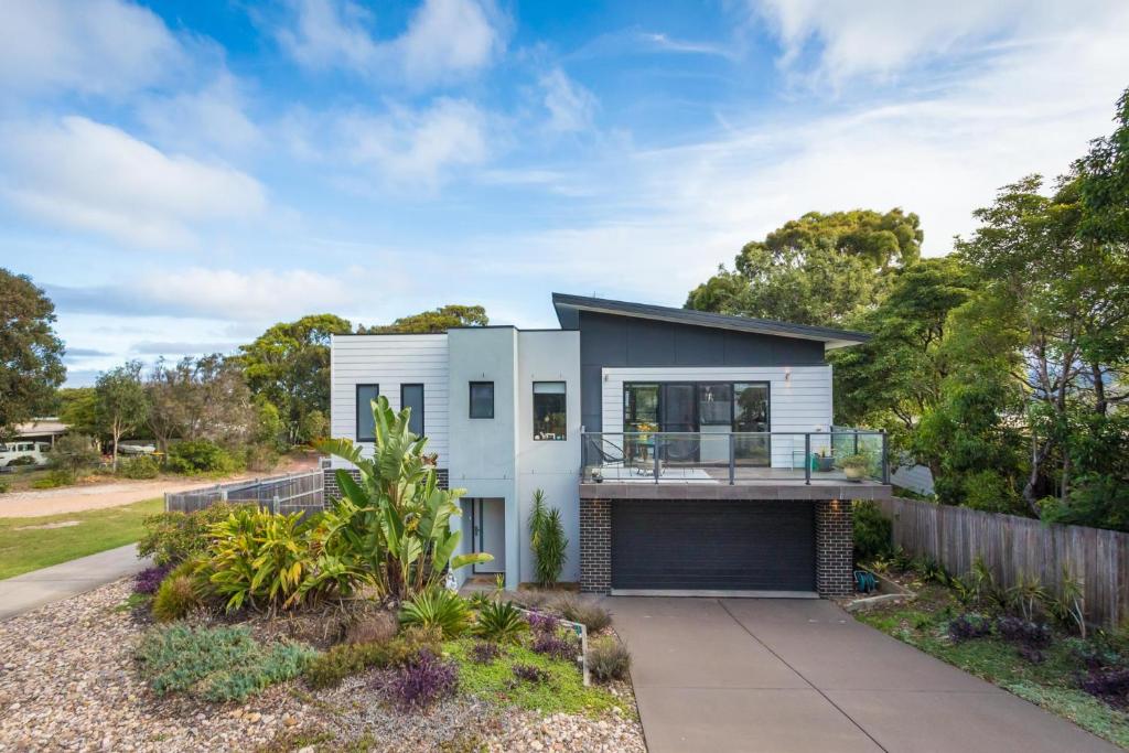 a white house with a balcony and a fence at Plan Beach in Merimbula