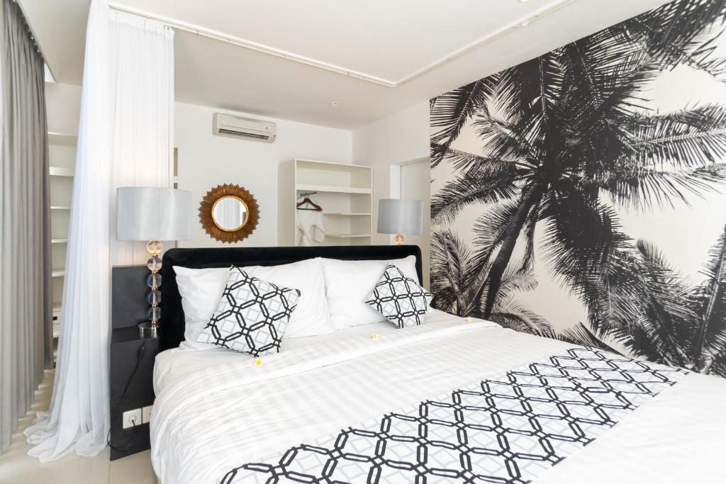 a bedroom with a black and white bed with a palm tree mural at Shanti Retreat in Seminyak