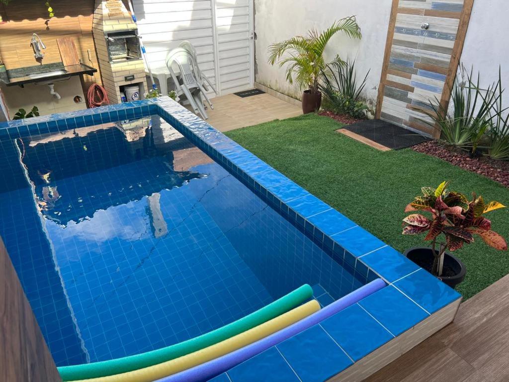 a swimming pool in a backyard with a lawn with a pool noodle at Casa Aconchegante com Piscina Barra do Jacuípe in Camaçari