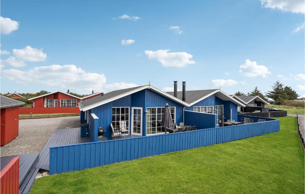ein blaues Gebäude mit grünem Rasen davor in der Unterkunft Pet Friendly Home In Hvide Sande With Sauna in Hvide Sande