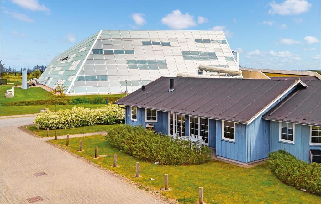 una casa blu di fronte a un edificio di vetro di 4 Bedroom Lovely Home In Nrre Nebel a Lønne Hede