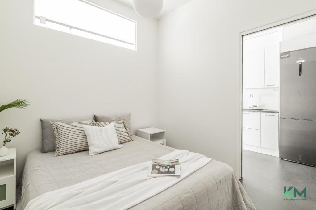 a white bedroom with a large bed and a window at Kotimaailma - Kaunis ja hyvin valoisa kaksio Vantaalta in Vantaa