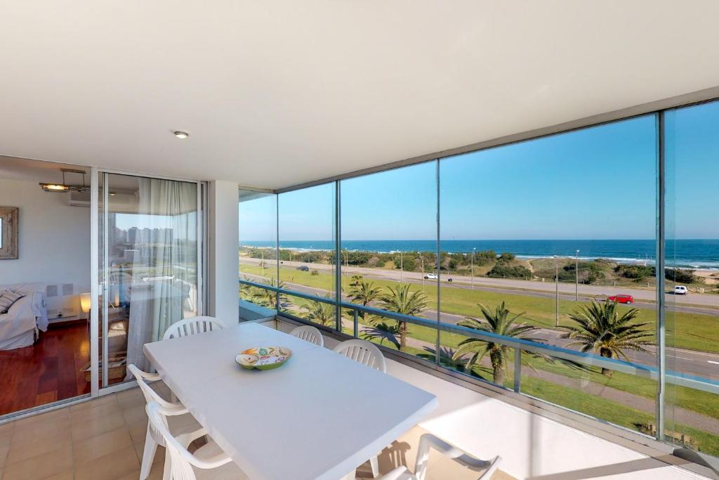 a dining room with a white table and views of the ocean at Oceana Suites en Esturion, frente a playa Brava in Punta del Este