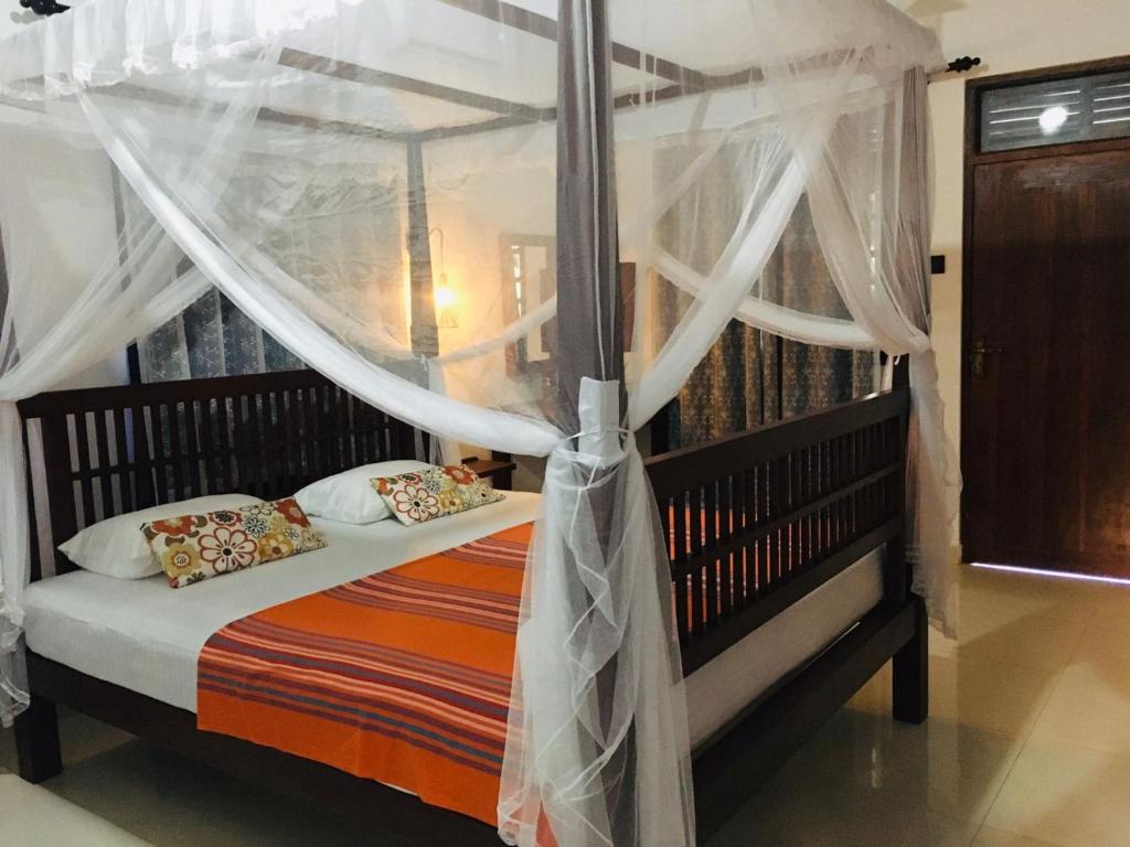 Schlafzimmer mit Himmelbett und weißen Vorhängen in der Unterkunft Sathis villa in Ambalangoda