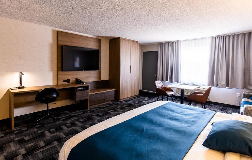 una camera d'albergo con letto, scrivania e TV di Auberge L'Étape a Mont-Laurier