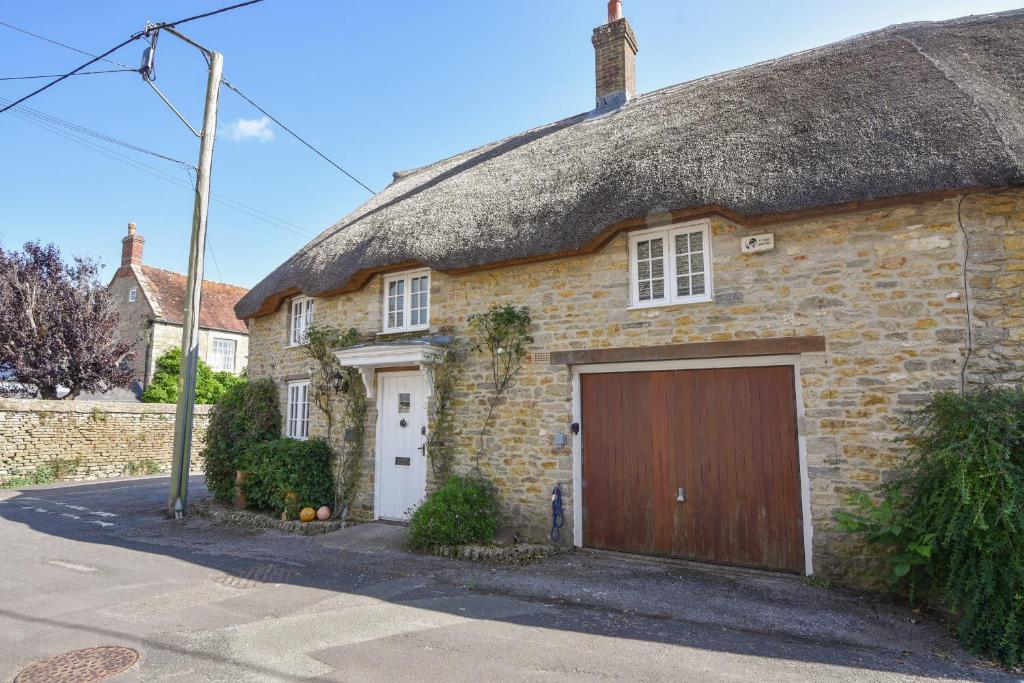a thatch roofed house with a garage at Stable Cottage in Bridport
