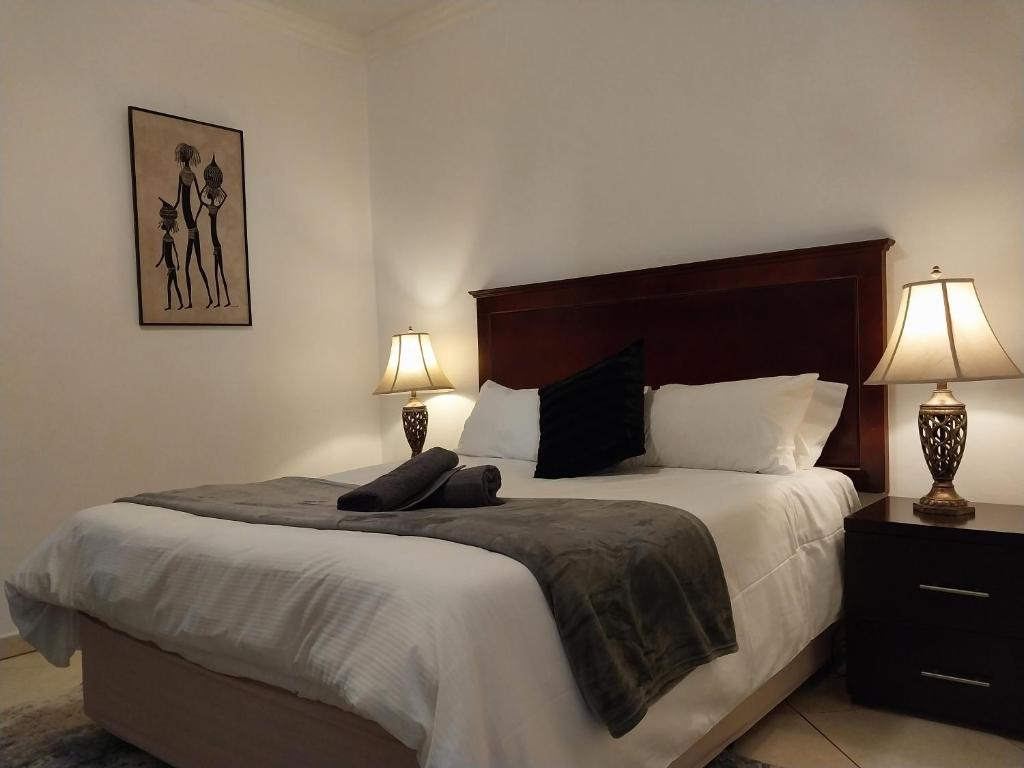 1 dormitorio con 1 cama grande y 2 lámparas en The Emerald, en Pretoria
