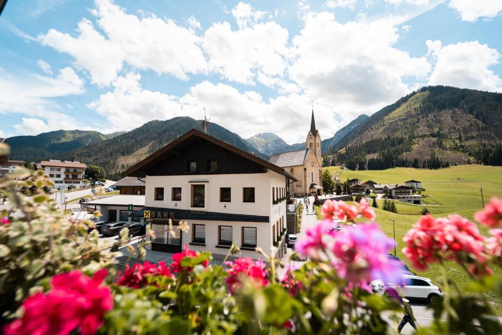 a village with a church and flowers in the foreground at Ferienwohnung Zedlacher in Kartitsch