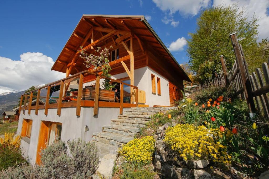 a small house with a wooden roof and some flowers at Chalet les Blancs in Eygliers