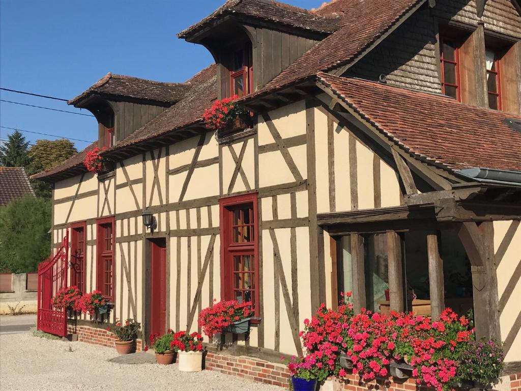 ein Gebäude mit roten Fenstern und Blumen davor in der Unterkunft Chambre d'Hôte du Pic Drille in Charmont-sous-Barbuise