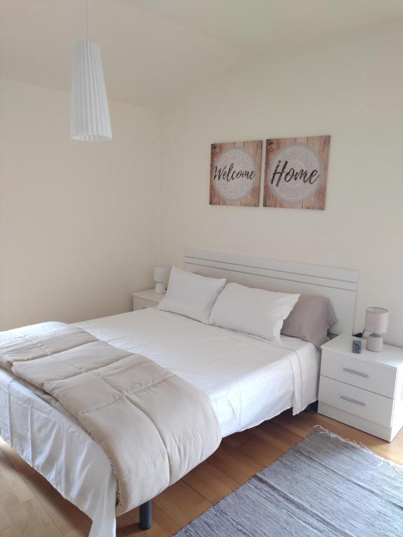 um quarto com uma cama grande e lençóis brancos em Apartamentos A Parada do Camiño Padrón em Padrón