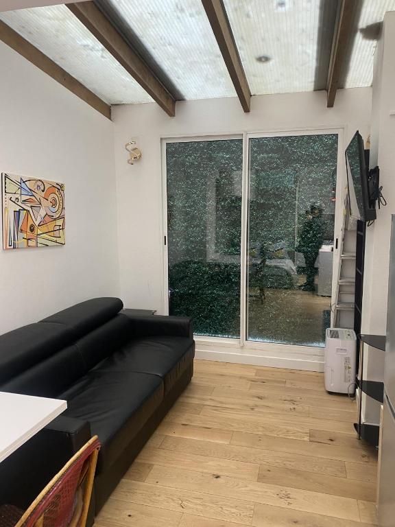 - un salon avec un canapé noir et une grande fenêtre dans l'établissement joli studio 2/4 personnes, à Paris