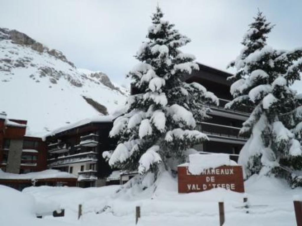 Appartement Val-d'Isère, 1 pièce, 6 personnes - FR-1-411-868 في فال ديزير: نزل التزلج مع الأشجار المغطاة بالثلج وإشارة