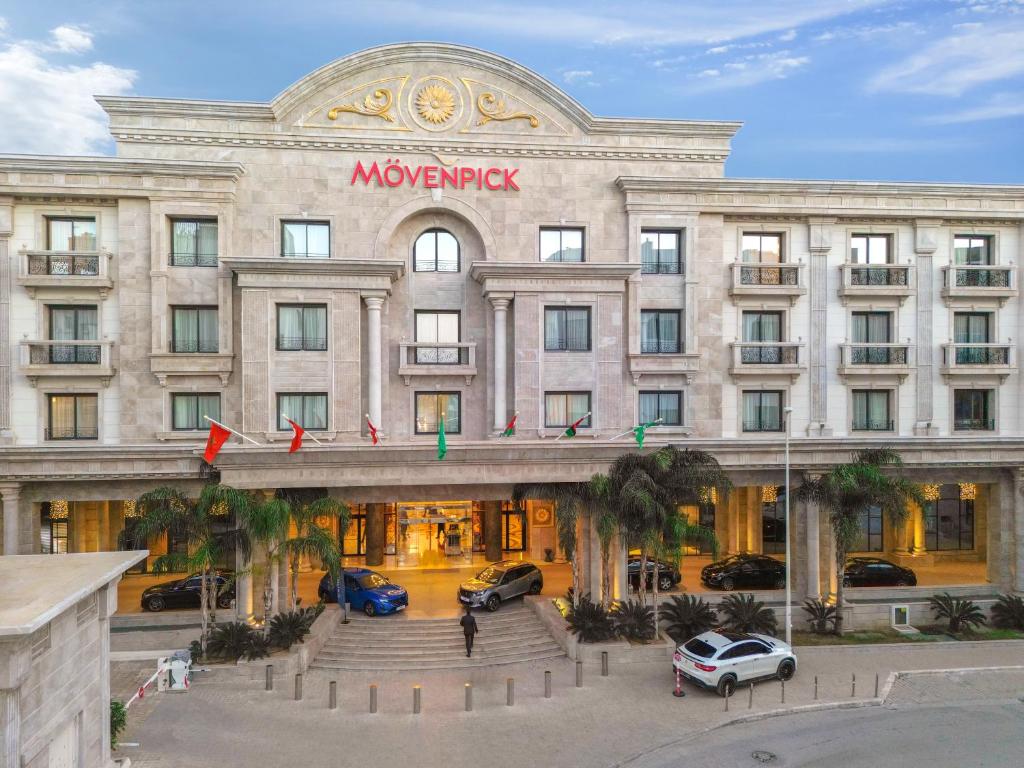 een groot gebouw met auto's geparkeerd voor het bij Mövenpick Hotel du Lac Tunis in Tunis