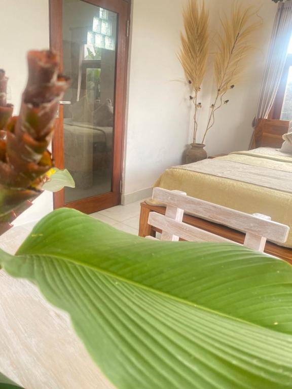 Habitación con 2 camas y una gran hoja verde. en Twin Inn 2, en Ubud