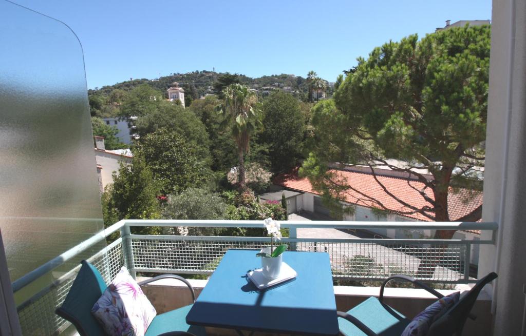 einen blauen Tisch auf einem Balkon mit Blick auf die Bäume in der Unterkunft Charming & quiet appart 10 from beaches in Cannes