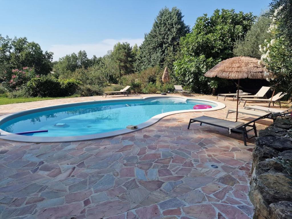 a swimming pool with a patio and an umbrella at Villa des Cigales in Trets