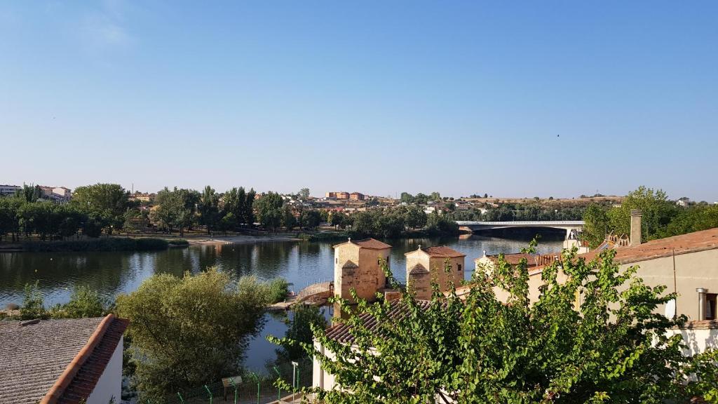 a view of a river with buildings and a bridge at La Casa del Río in Zamora