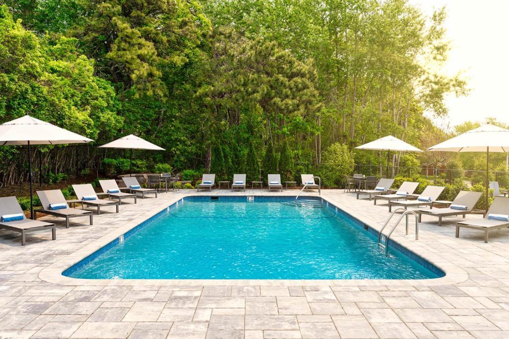 a swimming pool with chairs and umbrellas at Greyfinch Chatham Inn in Chatham