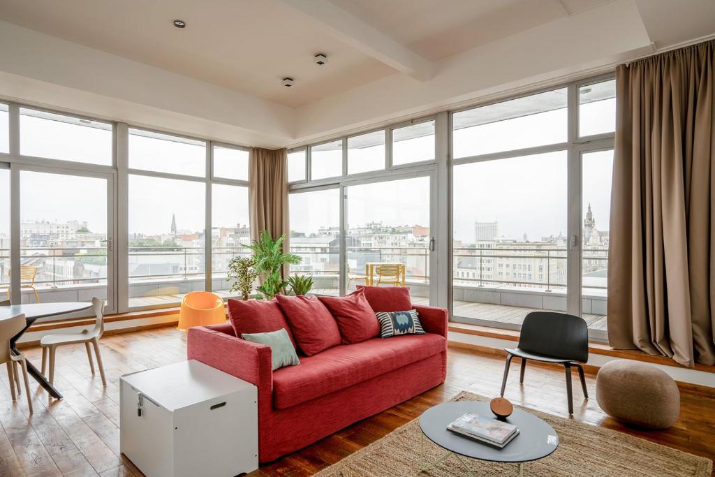 uma sala de estar com um sofá vermelho e janelas grandes em Smartflats - Central Antwerp em Antuérpia