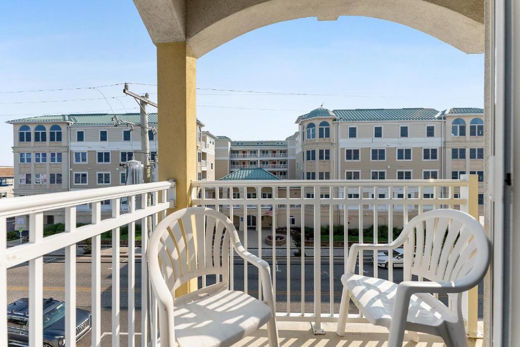 two chairs on a balcony with a view of buildings at Partial Ocean View Condo W Pool & Parking in North Wildwood