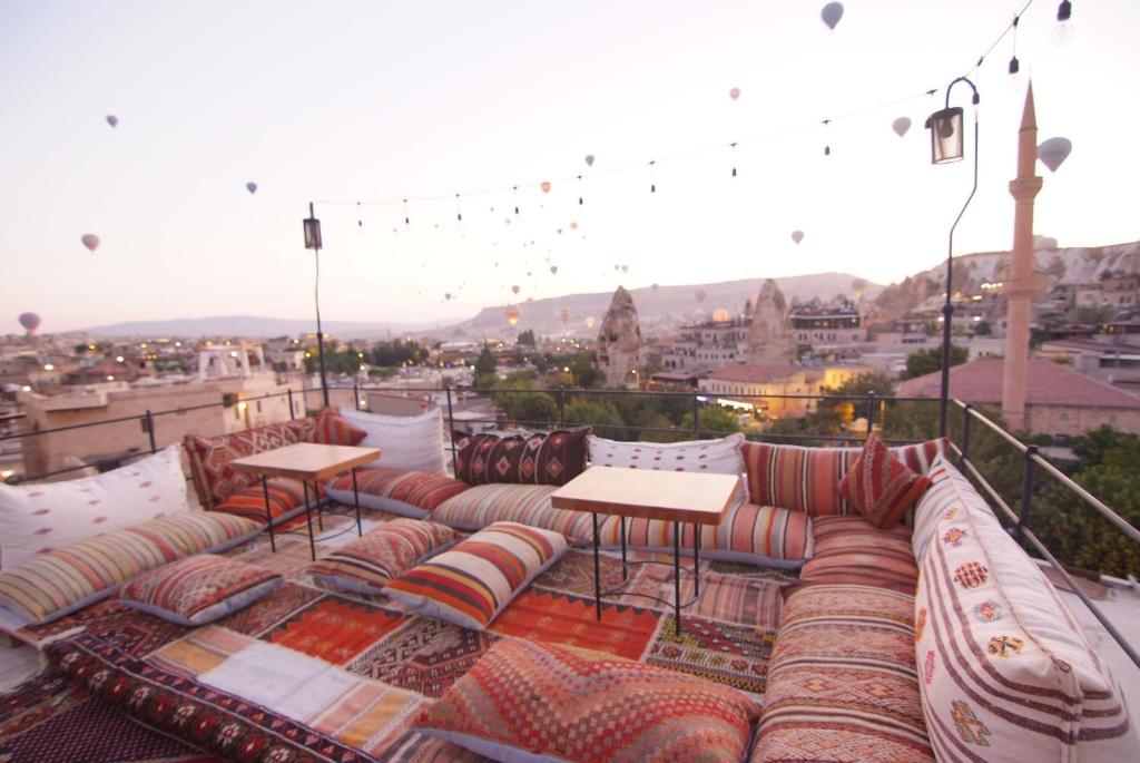 a rooftop patio with couches and tables and a view at Peruna Cave in Goreme