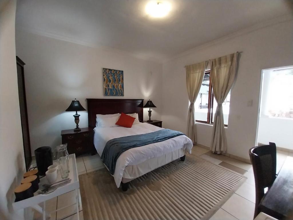 1 dormitorio con cama, mesa y ventana en The Coral, en Pretoria