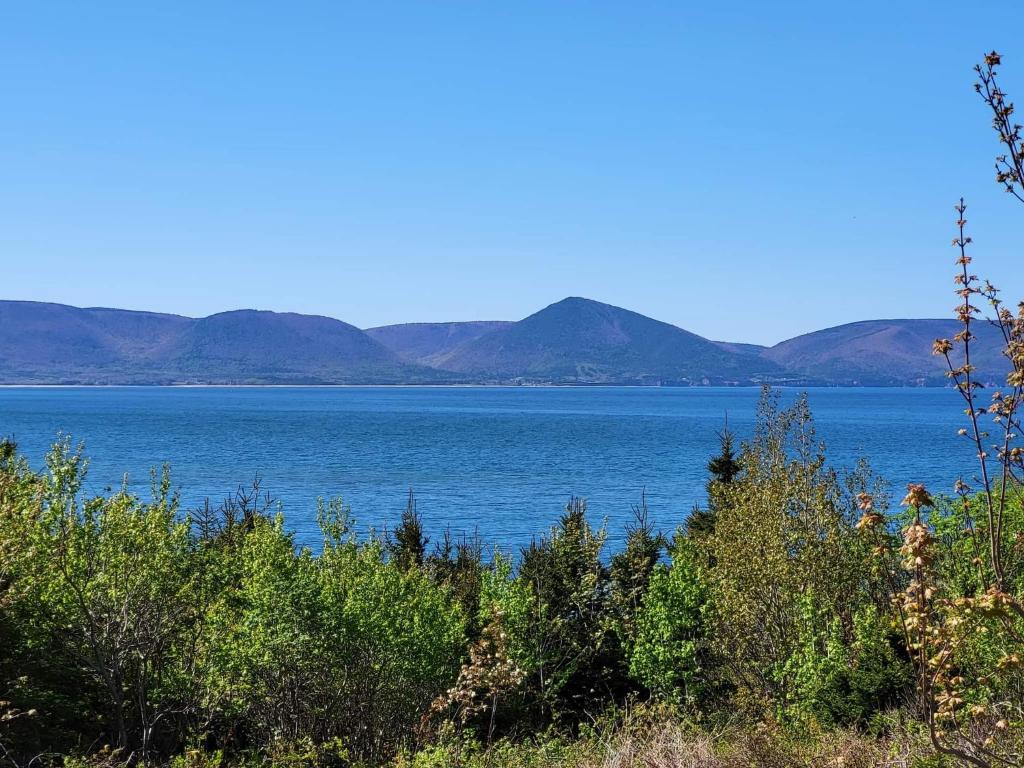 a view of a large body of water with mountains in the background at Moceanset Getaways - Ocean, Mountain & Sunset Views - Cozy Accommodations in Dingwall