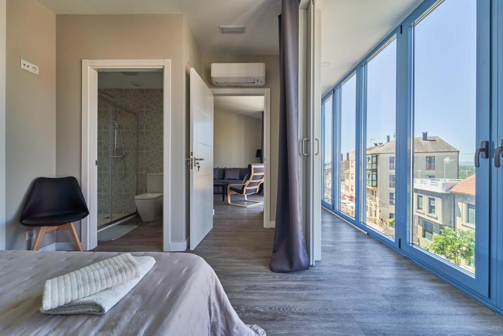 ein Schlafzimmer mit einem Bett und einem großen Fenster in der Unterkunft Apartamentos Carballal in Palas de Rei