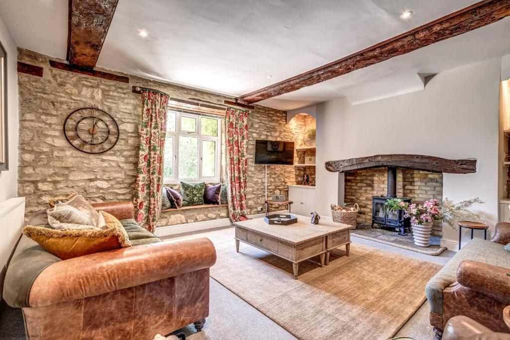 a living room with a couch and a fireplace at Greenhill Farmhouse in Bletchingdon