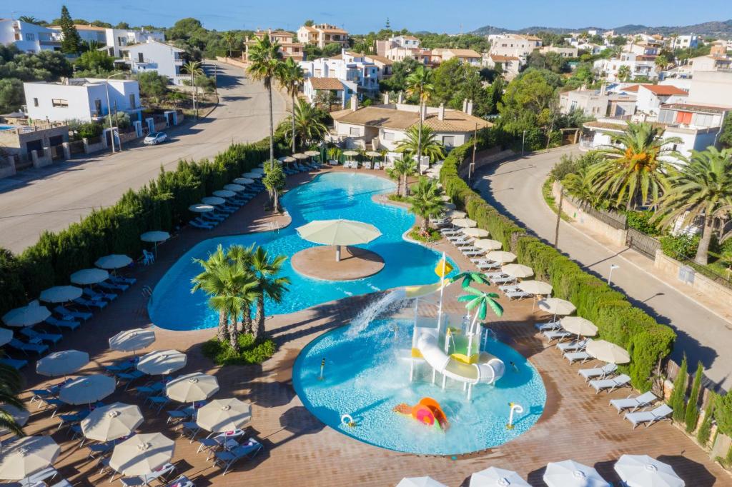 an aerial view of a resort pool with umbrellas and chairs at JS Portocolom Suites in Portocolom