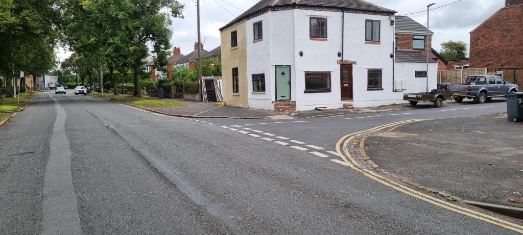 an empty street with a white house and a truck at One Lovely Apartmt 1 Double & 2 Camp Beds in Stoke on Trent