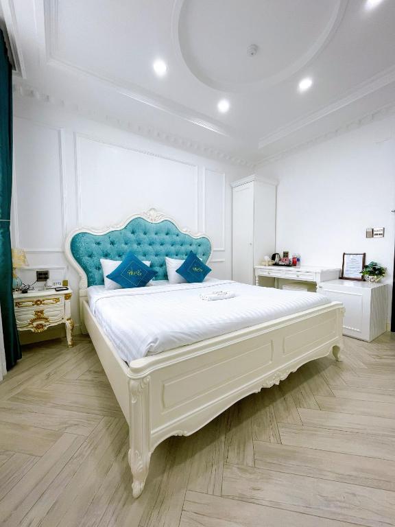 a bedroom with a large white bed with a blue headboard at Paris Hotel & Cafe in Vĩnh Long
