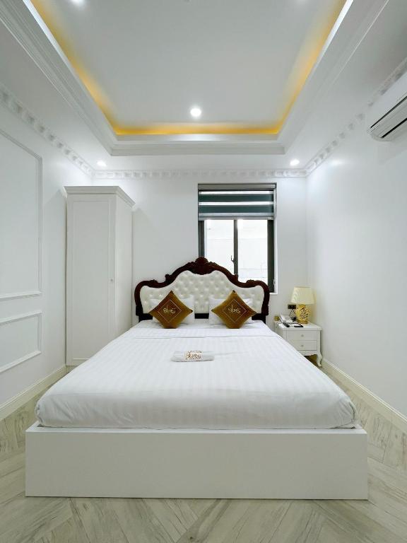 a white bedroom with a large white bed with a window at Paris Hotel & Cafe in Vĩnh Long