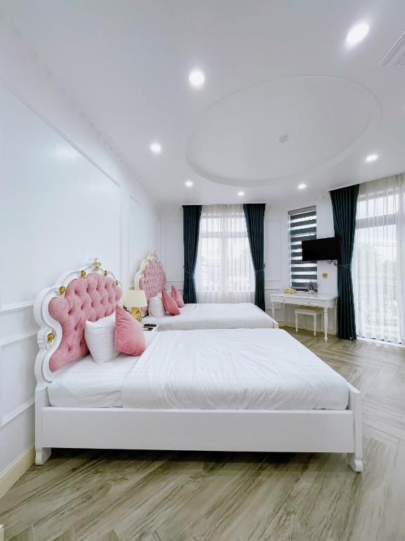 a white bedroom with two beds with pink pillows at Paris Hotel & Cafe in Vĩnh Long
