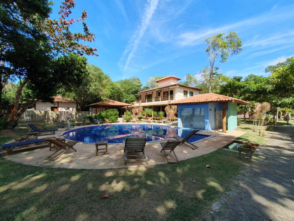 uma piscina com cadeiras e uma casa em Pousada Maré em Cumuruxatiba