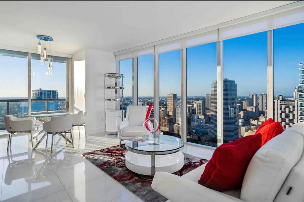 una sala de estar con muebles blancos y ventanas grandes. en PENTHOUSE 2BR ICON WHOTEL Brickell Miami en Miami